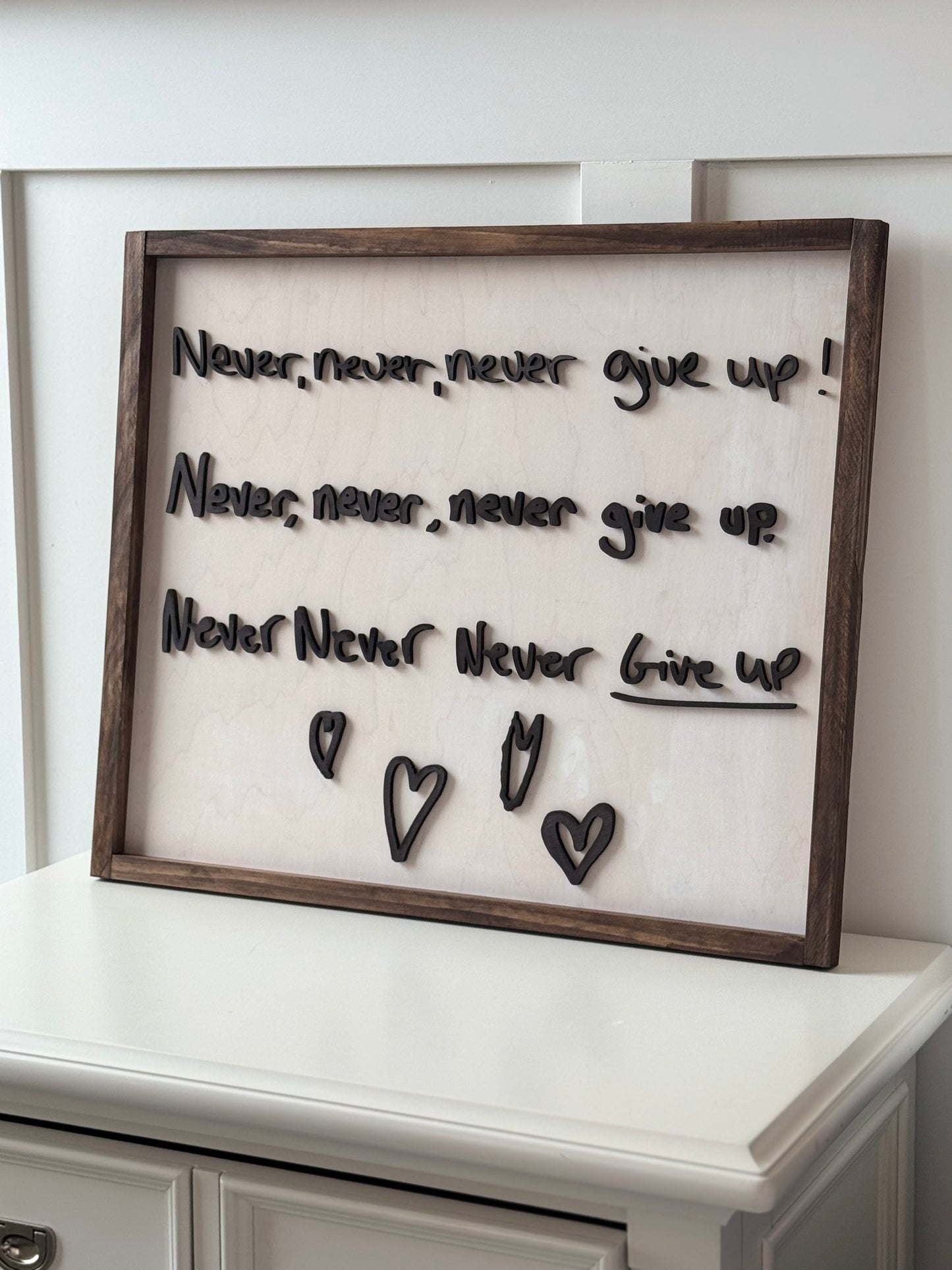 Decorative wall art with motivational text and heart shapes in a wooden frame.